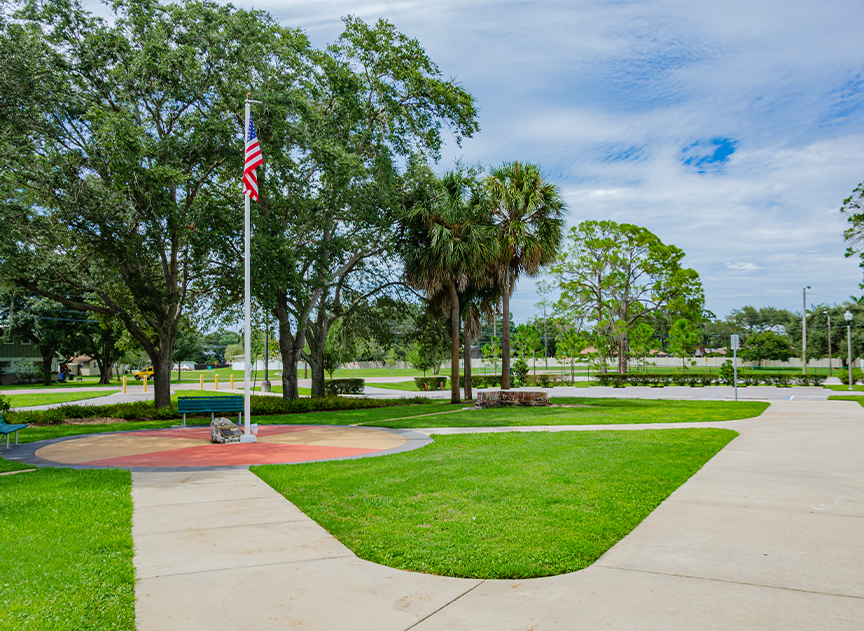A circular seating area at Riviera Bay Park with benches and a flag pole