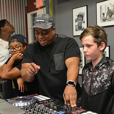 Teens watching the tech camp instructor demonstrate how to DJ.