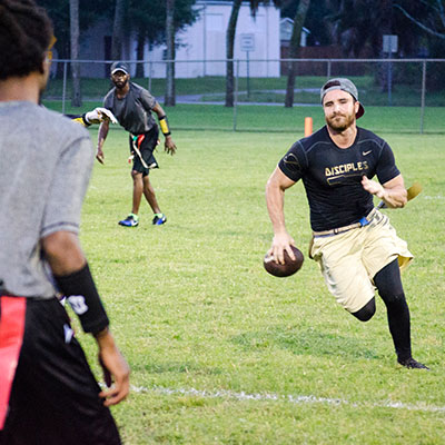 Adult man running with football in our adult league