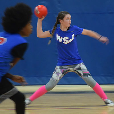 Girl throwing a dodgeball participating in our teen dodgeball league